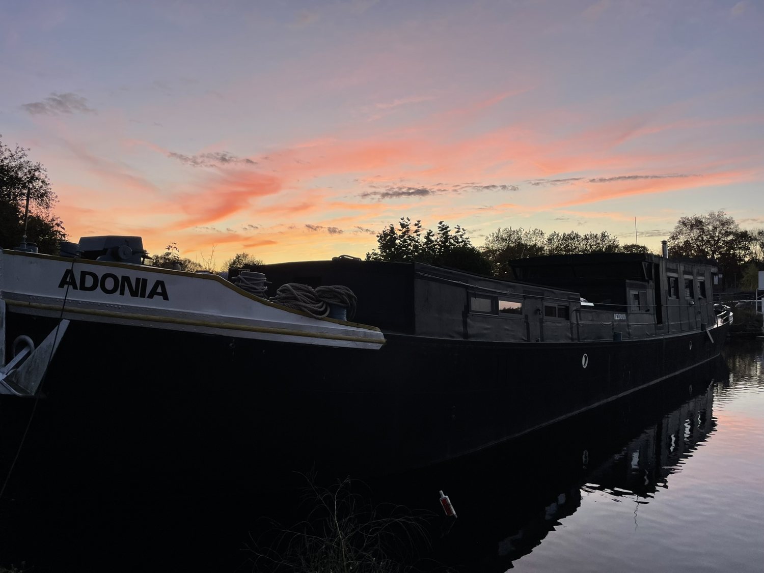 Woonboot MS Adonia op het water bij zonsondergang